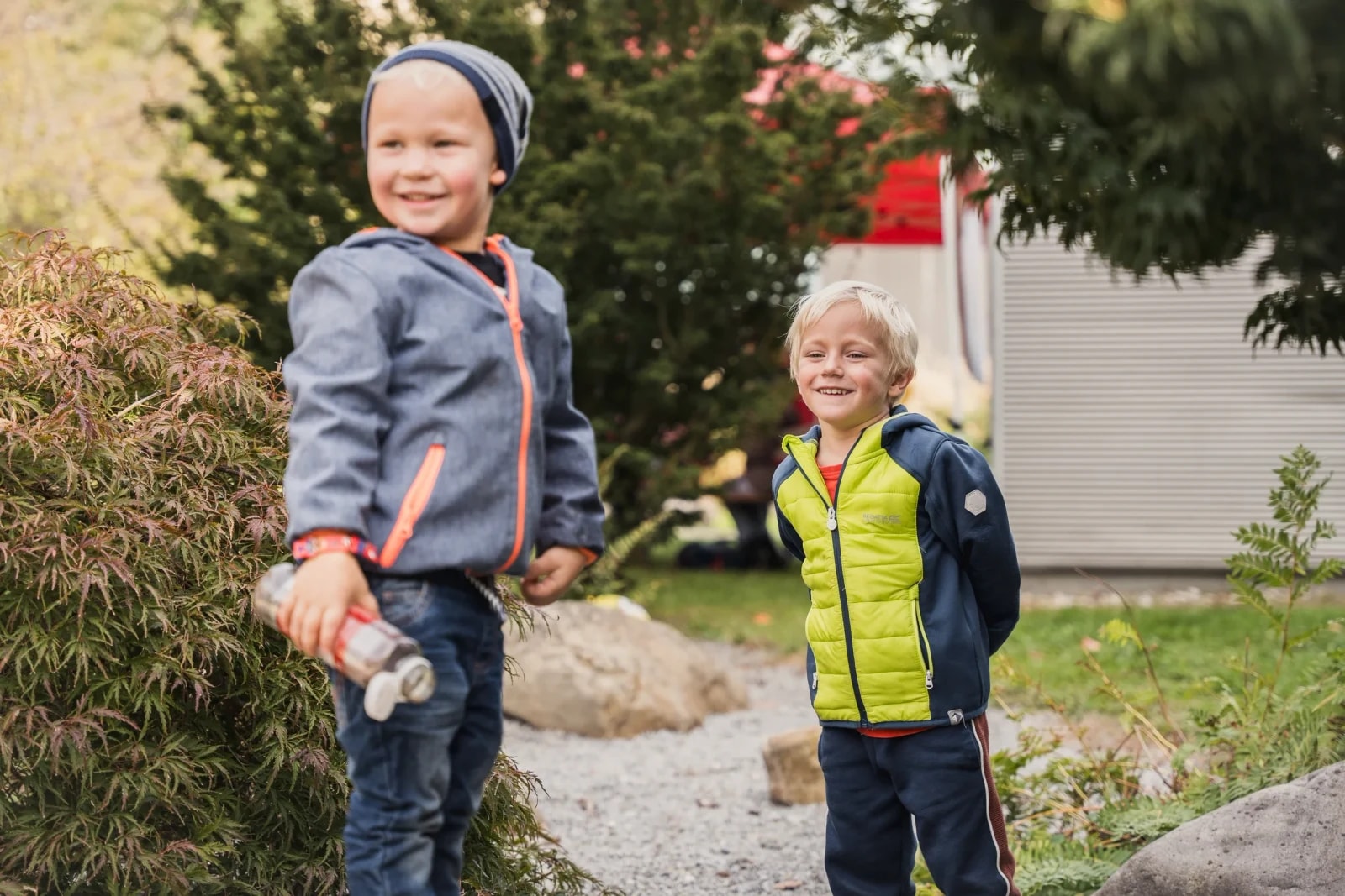 Zwei Buben in Herbstkleidung spielen im Garten eines Kinderfreunde-Standorts.