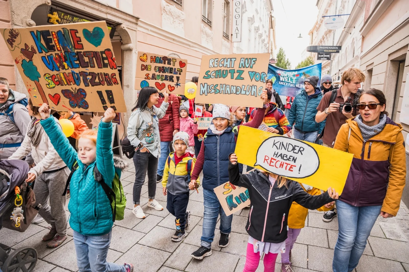 Demozug mit Kindern und Eltern, Schilder „Kinder haben Rechte!" und „Recht auf Schutz vor Misshandlung".