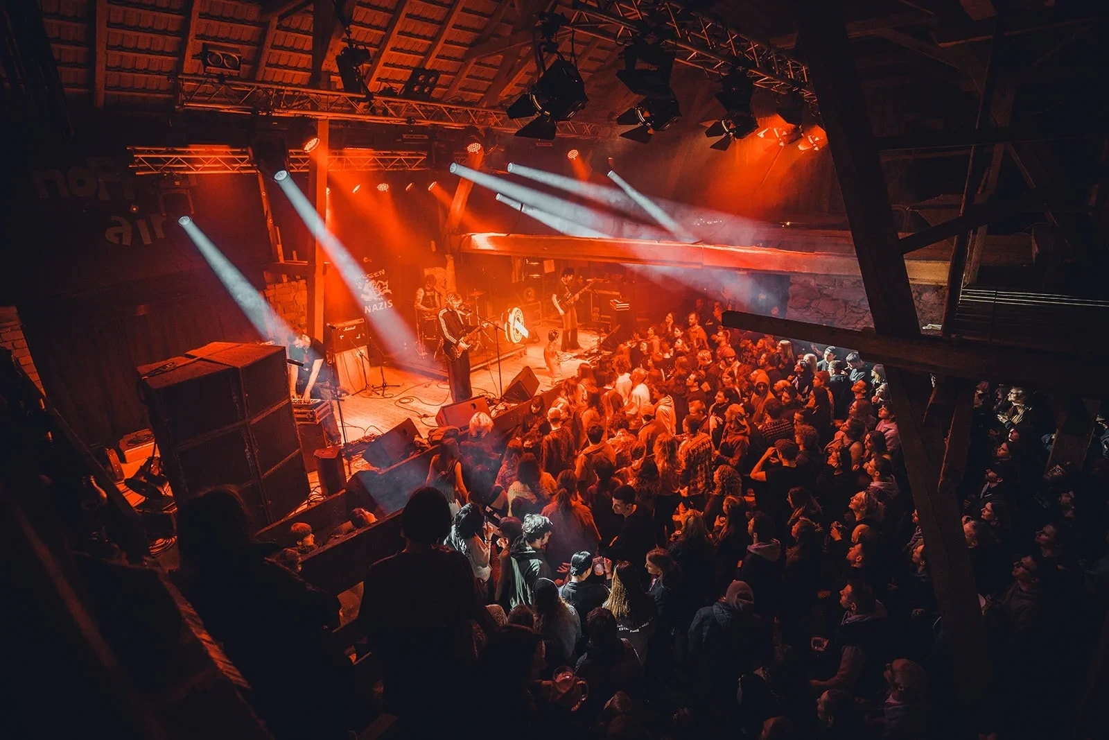 Blick von oben in die volle Konzerthalle des NoppenAir Festivals mit Bühne, Lichtstrahlen und Publikum.
